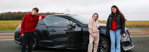 kids stood in front of a bentley